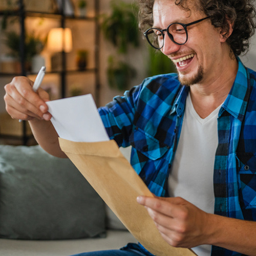 Adult man work from home and open letter from envelope with good news