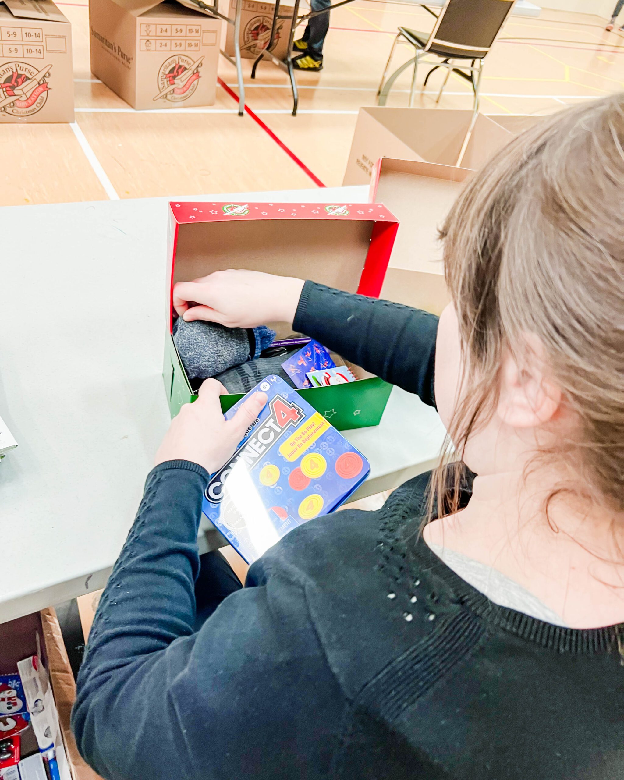 Operation Christmas Child - woman placing items in box