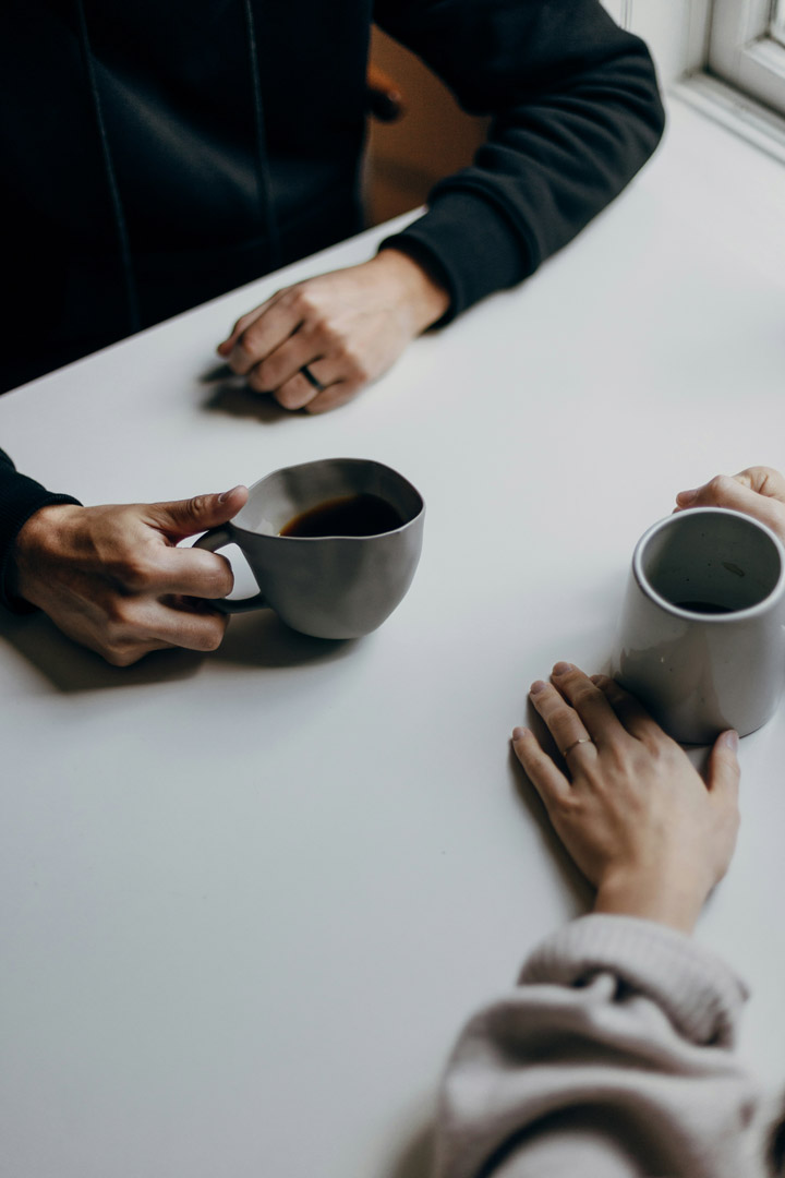 top down of hands on a table, with coffee cups