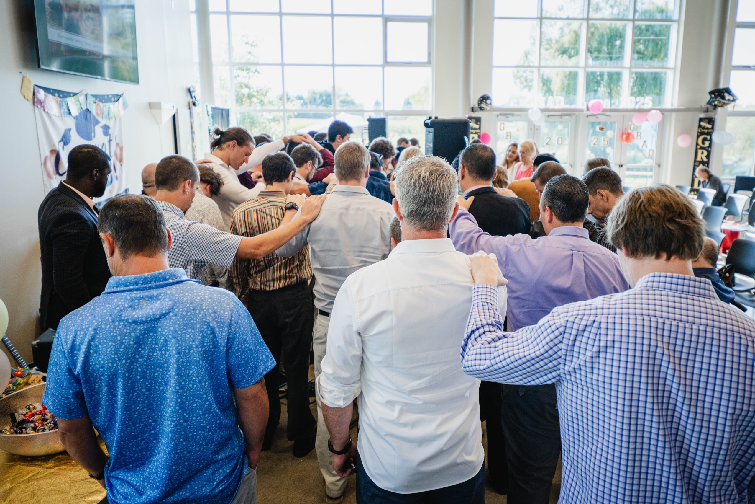 Group of people with hands resting on shoulders, in prayer