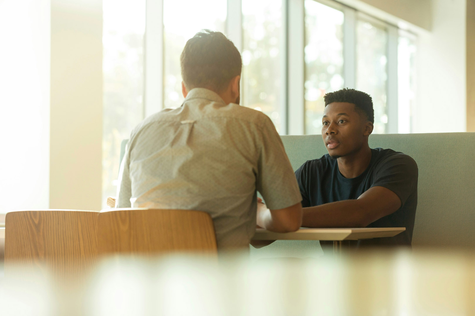 Two men conversing in a private booth