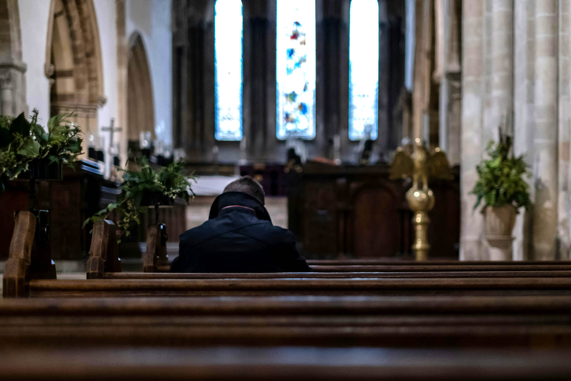 Man sitting in church pew, facing front of church