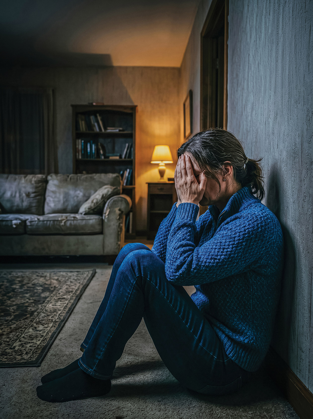 Woman with hands in head, leaning against wall.